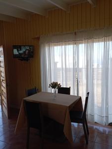 una mesa de comedor con un jarrón de flores. en Cabaña Curanipe Playa, en Curanipe