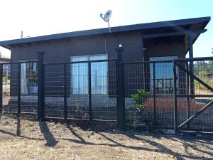 a fence in front of a house at Cabaña Curanipe Playa in Curanipe