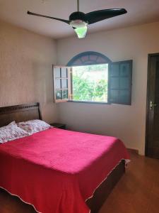 1 dormitorio con cama roja y ventana en Refúgio Bonanza en Teixeiras