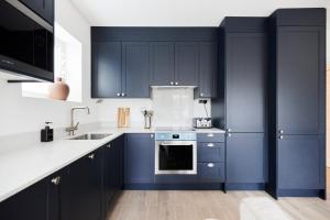 una cucina con armadi blu scuro e lavandino di The Wembley Park Retreat - Modern 2BDR Flat with Balcony a Londra