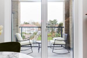 een kamer met een balkon met stoelen en een tafel bij The Wembley Park Retreat - Modern 2BDR Flat with Balcony in Londen