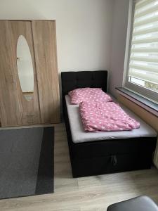 ein kleines Schlafzimmer mit einem Bett mit einer rosa Decke in der Unterkunft FeWo und Monteurzimmer Wesel in Wesel