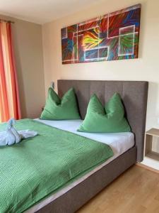 - une chambre dotée d'un lit avec des oreillers verts et un tableau dans l'établissement Zweytick Gästezimmer Weingut, à Ratsch an der Weinstraße