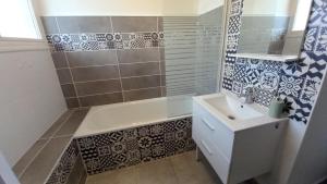 een badkamer met een wastafel, een bad en tegels bij Le Voltaire -2 chambres- 70m2- HYPERCENTRE-Parking-WIFI FIBRE in Tarbes