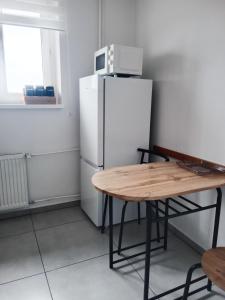 een keuken met een tafel en een witte koelkast bij Mieszkanie Turkus w Gnieźnie in Gniezno