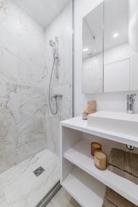 uma casa de banho branca com um chuveiro e um lavatório. em Imhost 8 - Lovely studio at St Michel-Notre Dame em Paris