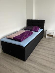 Bett mit violetter Bettwäsche und einem schwarzen Kopfteil in der Unterkunft FeWo und Monteurzimmer Wesel in Wesel