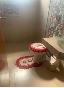 baño con aseo rojo y blanco en el suelo en Linda Casa Próximo Aeroporto en Campo Grande