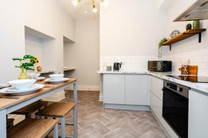 a kitchen with white cabinets and a wooden table at Stay Coastal in Whitley Bay