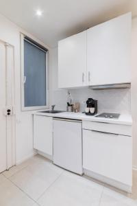 uma cozinha branca com armários brancos e uma janela em Imhost 8 - Lovely studio at St Michel-Notre Dame em Paris