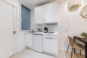 uma cozinha branca com armários brancos e uma mesa em Imhost 8 - Lovely studio at St Michel-Notre Dame em Paris