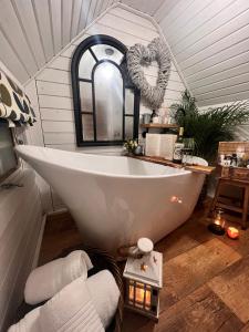 uma banheira branca na casa de banho com um espelho de coração em 1 - Incredible Views - Outdoor Bathtub - Unique Style em Pont Sticill