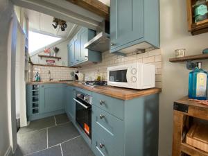 a kitchen with blue cabinets and a microwave at Cosy Fisherman’s Cottage: 150m to Brixham Harbour in Brixham