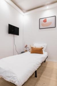 um quarto branco com uma cama e uma televisão de ecrã plano em Imhost 8 - Lovely studio at St Michel-Notre Dame em Paris