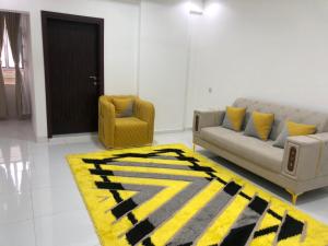 uma sala de estar com um sofá e um tapete amarelo e preto em ANTIKA HOTEL / انتيكا للشقق الفندقيه em Firq