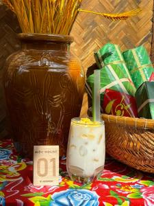 una vela en un vaso sobre una mesa junto a un jarrón en Mộc House, en Kon Tum Kơ Pang