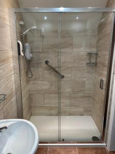 una ducha con una puerta de cristal junto a un lavabo en The Glen Hotel Newtonmore, en Newtonmore