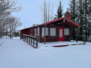 Cabaña roja con techo rojo en la nieve en Lakeview cabin near Kirkjubaejarklaustur, en Kirkjubæjarklaustur