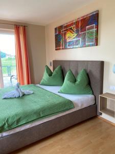 1 dormitorio con 1 cama grande con almohadas verdes en Zweytick Gästezimmer Weingut, en Ratsch an der Weinstraße