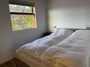 1 cama blanca en un dormitorio con ventana en Lakeview cabin near Kirkjubaejarklaustur, en Kirkjubæjarklaustur