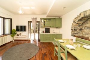 une cuisine avec des placards verts et une table avec des chaises dans l'établissement Rustico con idromassaggio vista lago, à Brienno