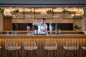 Ein Mann steht an einer Bar und gießt einen Drink ein in der Unterkunft Malena Hotel & Suites - Adults Only by Omilos Hotels in Ammoudara