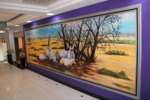 Garden Hotel Muscat By Royal Titan Group في مسقط: لوحة كبيرة للخيول على جدار في الممر