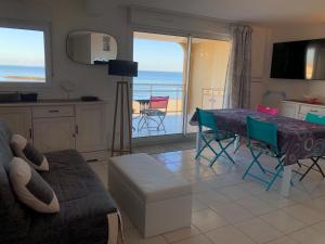 a living room with a table and a kitchen with the ocean at Appartement Front de mer in Valras-Plage