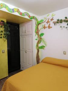 a bedroom with a tree and birds on the wall at Casa los Arcos Oaxaca in Oaxaca City