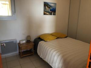 a small bedroom with a bed and a night stand at Appartement Front de mer in Valras-Plage
