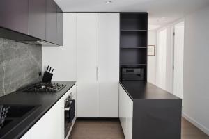 a kitchen with white cabinets and a black counter top at 'Modern Minimalism' Slate Chic in the City in Melbourne