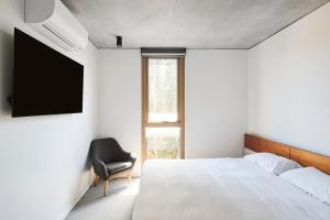 a bedroom with a bed and a chair and a television at 'Modern Minimalism' Slate Chic in the City in Melbourne