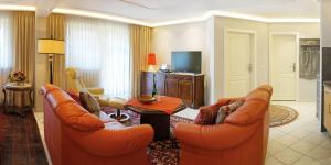 a living room with orange couches and a television at Europa Residenz Premium Suite in Bad Füssing