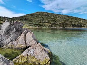 a large rock in the water next to a mountain at ECO CABAÑA INTIWAT'A in Comunidad Challapampa