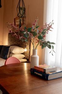 uma mesa com dois livros e um vaso com flores em Hartland Huis em Graaff-Reinet