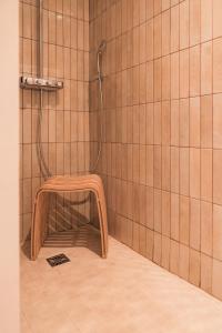 a shower with a wooden stool in a tiled bathroom at L'esquisse Barbizon - Teritoria in Barbizon