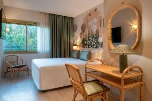 a bedroom with a bed and a table and a mirror at Résidence Hôtelière Chambord in Menton