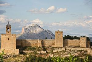 a castle with a clock tower and a mountain in the background at Casita tentación con jacuzzi Privado in Málaga