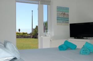 a bedroom with a tv and a bed with blue pillows at Tywyn Beach House in Tywyn