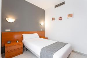 a bedroom with a white bed and a wooden headboard at Hotel Alda Ciudad de Toro in Toro