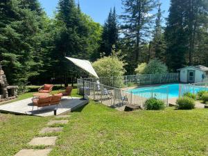 a patio with a chair and a umbrella next to a pool at Luxury St-Sauveur Chalet with Swim Spa Close to Ski in Sainte-Adèle