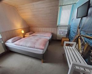 a bedroom with two beds and a tv and a bench at B & B Gästehaus Schmidt in Lichtenberg