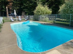 a blue swimming pool with chairs and a fence at Luxury St-Sauveur Chalet with Swim Spa Close to Ski in Sainte-Adèle