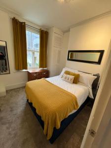 a bedroom with a bed with a yellow blanket on it at Central London Apartment (1) in London