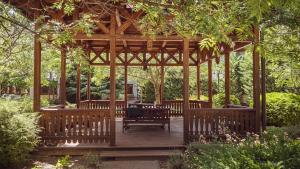 a wooden gazebo with a table and chairs at Hétkúti Wellness Hotel in Mór