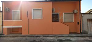 una pared naranja con dos ventanas y una puerta en Sa Brobei, en Simaxis