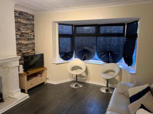 een woonkamer met een bank en 2 stoelen voor een raam bij Contractor & Family Friendly House Romford in Havering atte Bower