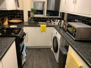 een keuken met witte kasten en een wasmachine en droger bij Contractor & Family Friendly House Romford in Havering atte Bower