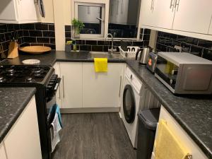a kitchen with white cabinets and a washer and dryer at Contractor & Family Friendly House Romford in Havering atte Bower