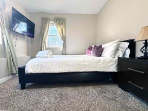 um quarto com uma cama com lençóis brancos e almofadas roxas em 415 Holland Springs em Kennesaw